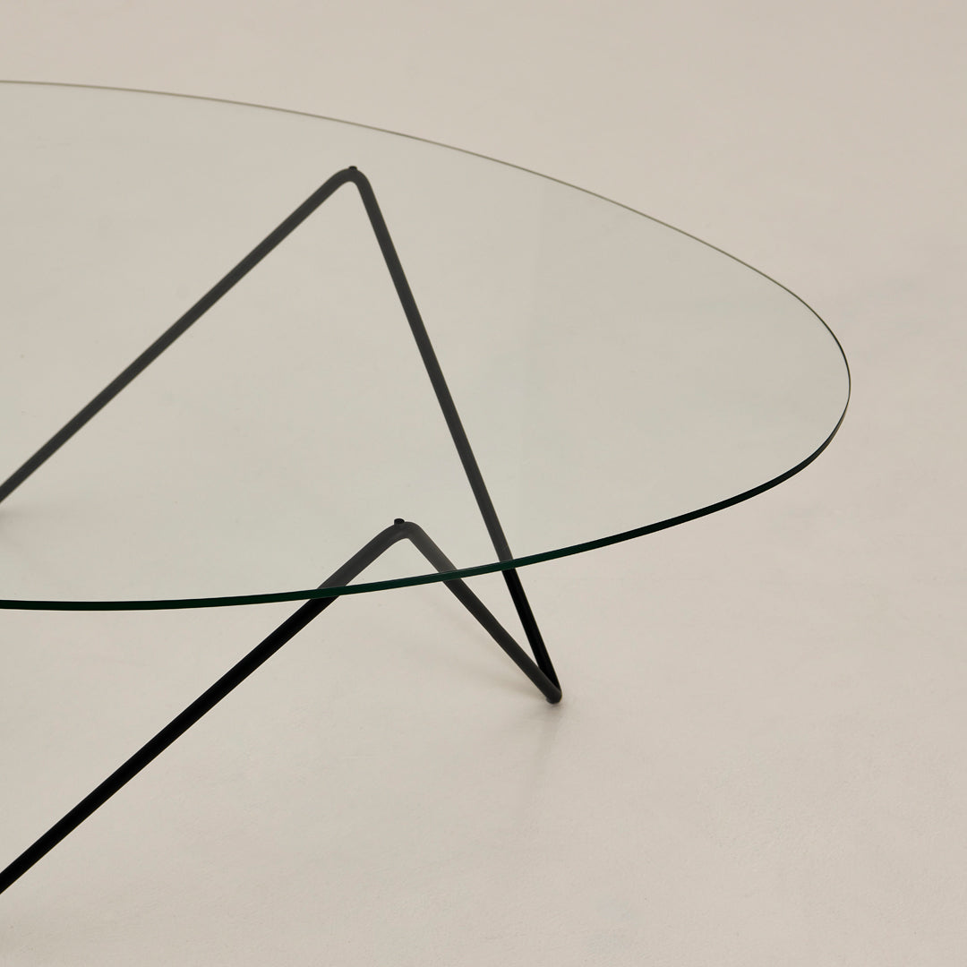 Clear glass table with sleek black metal legs, featuring a minimalist design and modern aesthetic.