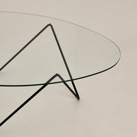 Clear glass table with sleek black metal legs, featuring a minimalist design and modern aesthetic.