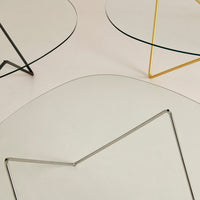 Geometric glass tables with black, silver, and gold frames, featuring modern and minimalist designs.