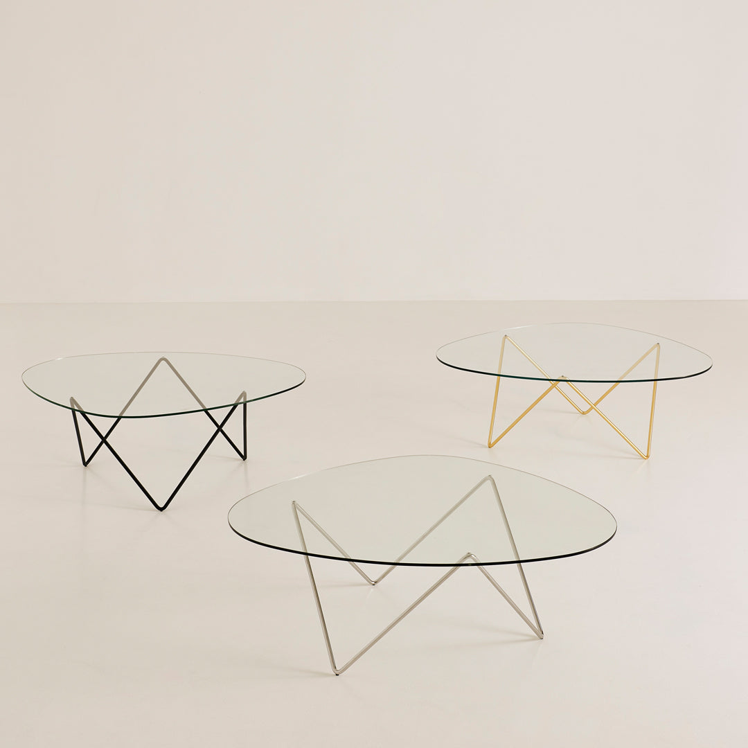Modern glass coffee tables with geometric metal bases in black, silver, and gold, featuring minimalist designs.