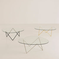 Modern glass coffee tables with geometric metal bases in black, silver, and gold, featuring minimalist designs.