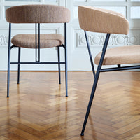 Contemporary tan upholstered chairs with sleek black metal legs, featuring a textured fabric pattern.