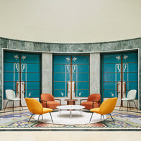 Vibrant blue walls and patterned area rug complement orange, yellow, and white chairs in modern seating arrangement.