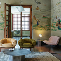"Living room featuring pastel-colored chairs in yellow, green, and pink against a muted, patterned wall."