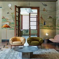 "Elegant armchairs in mustard yellow and olive green, set against a beautifully patterned mural and soft gray rug."