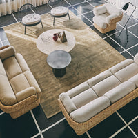 Neutral beige and cream sofas on a textured tan rug, with a geometric black and white patterned floor.