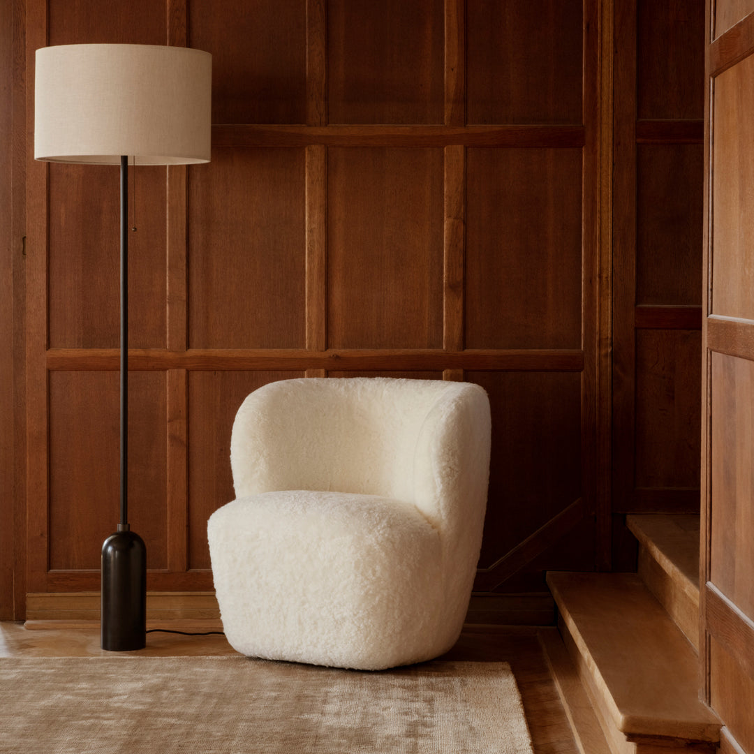Cozy white textured chair against a warm wood-paneled wall and neutral rug.