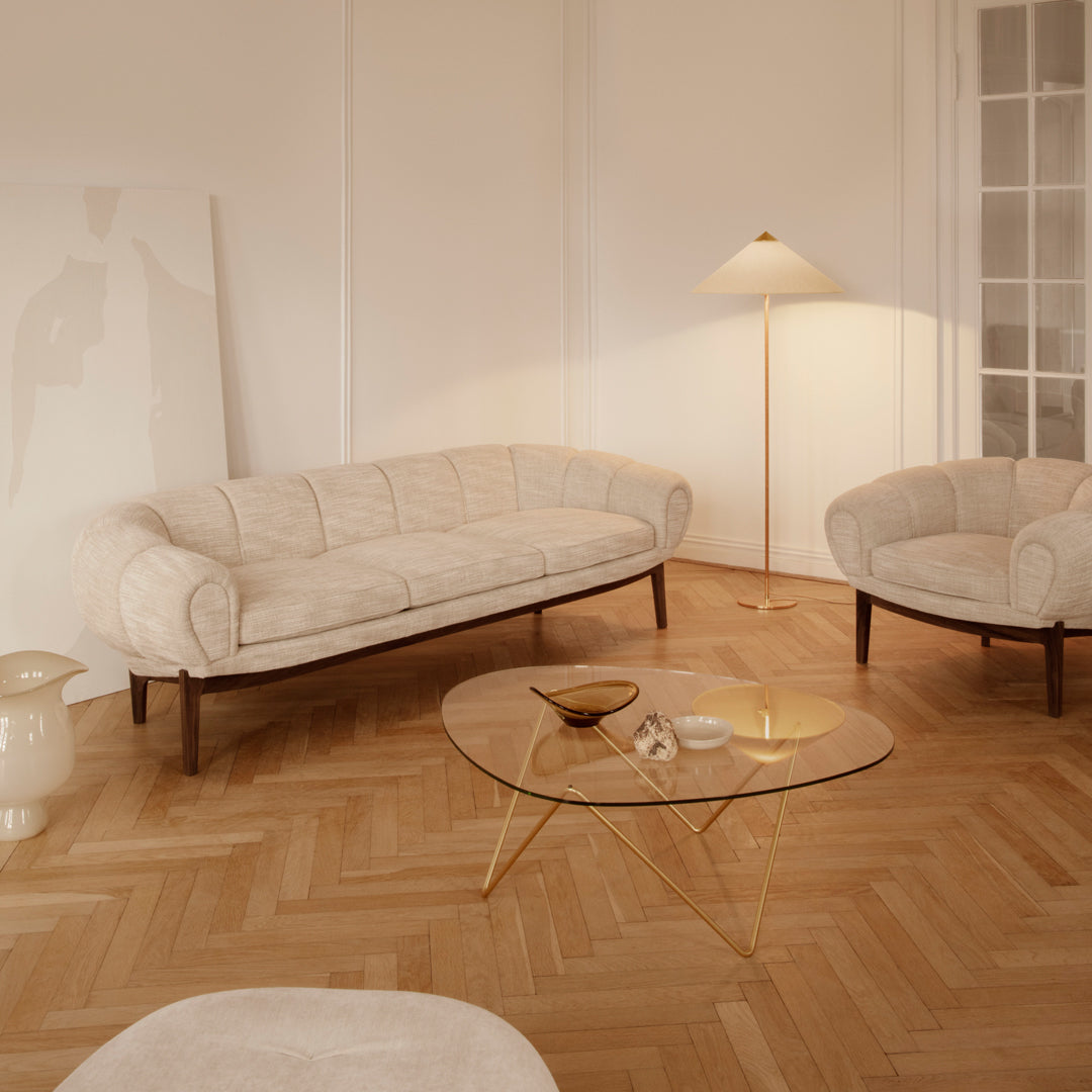 Cream textured sofa and chair set with gold accents, set on a warm wood floor in a minimalistic living room.