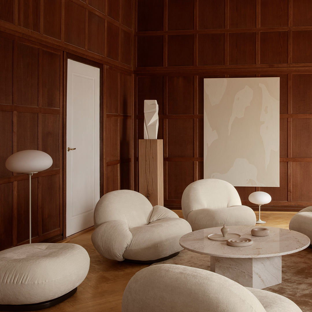 Soft beige upholstery against rich wood tones, complemented by abstract wall art and minimalistic white lighting.