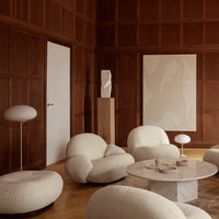 Soft beige upholstery against rich wood tones, complemented by abstract wall art and minimalistic white lighting.