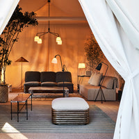 Cozy indoor lounge with neutral tones, beige fabrics, and soft green accents. Modern patterns and warm lighting create a serene vibe.