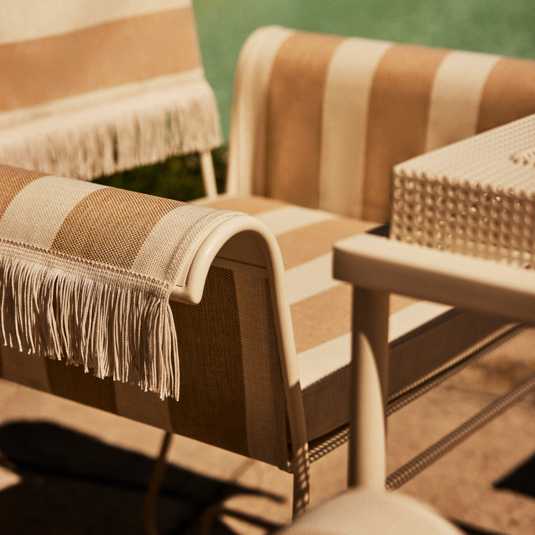 Beige and cream striped chairs with fringe detail, perfect for stylish outdoor lounging.