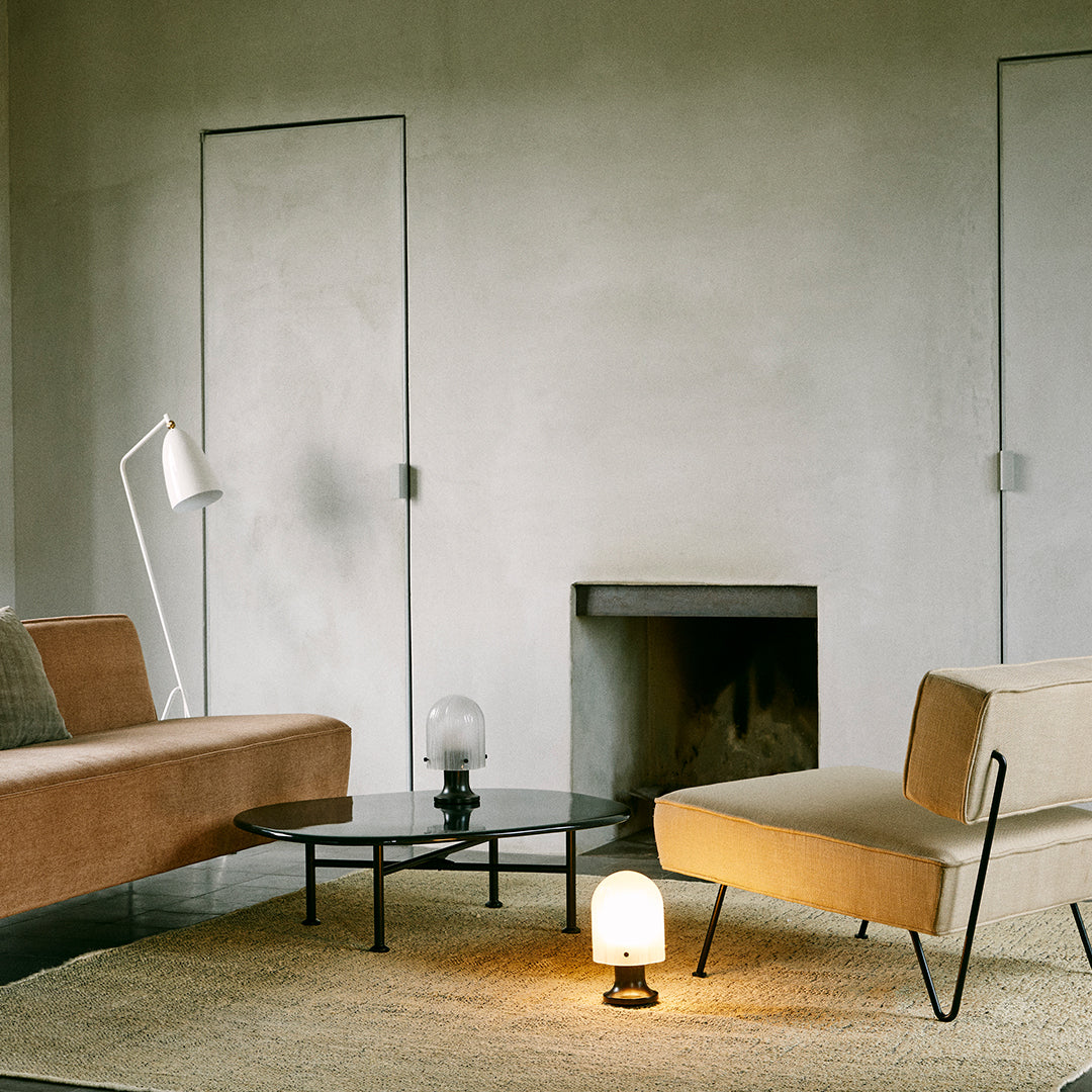 Modern living room featuring muted beige and brown furniture, a round black table, and a soft textured rug.