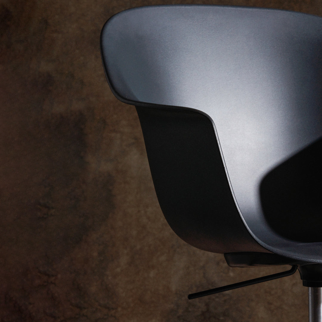 Black ergonomic chair with a smooth surface, set against a textured brown backdrop. Modern design and minimalist style.
