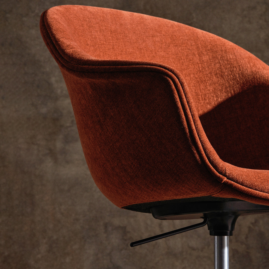 Orange fabric chair with a smooth finish and sleek design against a textured gray background.