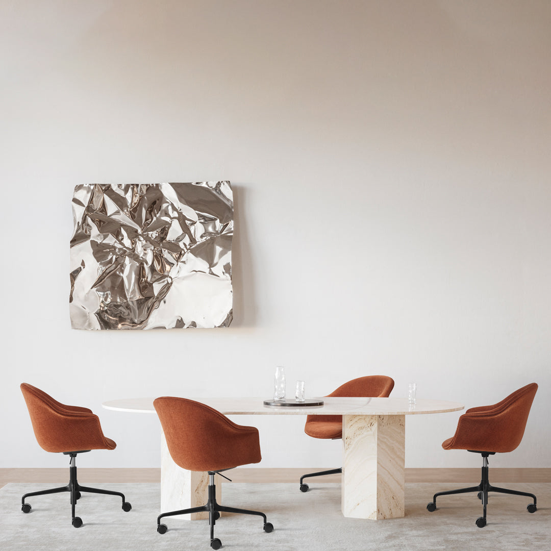 "Abstract silver and white wall art above a beige marble table with rust-colored chairs in a minimalist setting."