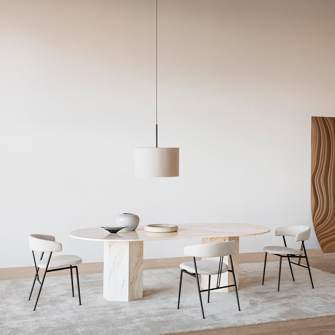 Modern beige dining table with cream chairs on a textured gray rug, minimalist design with soft color palette.