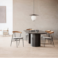Modern dining table with a sleek black finish, surrounded by light wood and white upholstered chairs against a soft beige backdrop.