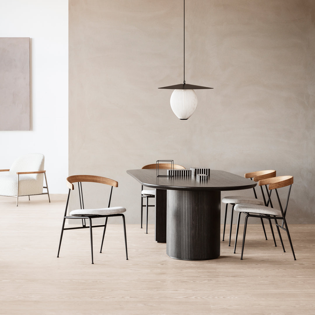 Modern dining table with a black finish, complemented by light wood and neutral-toned chairs in a minimalist setting.