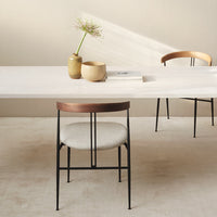 White table with natural wood accents, black metal legs, and neutral upholstered chairs, creating a minimalist modern look.