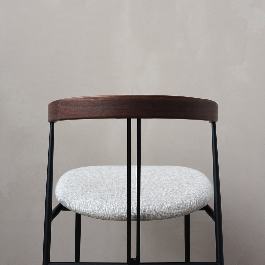 Modern black metal chair with a sleek walnut wood backrest and soft gray textured cushion. Perfect for contemporary decor.