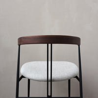 Modern black metal chair with a sleek walnut wood backrest and soft gray textured cushion. Perfect for contemporary decor.