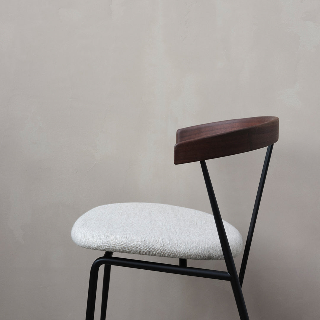 Gray upholstered chair with a sleek black metal frame and a rich wooden backrest. Minimalist design with soft textures.
