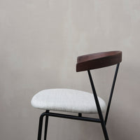 Gray upholstered chair with a sleek black metal frame and a rich wooden backrest. Minimalist design with soft textures.