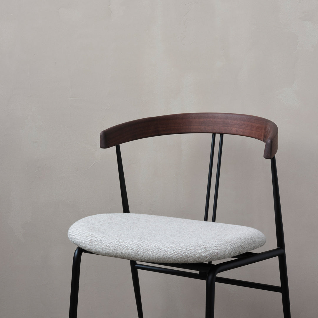 Gray upholstered seat on a sleek black metal frame with a brown wooden backrest, enhancing modern minimalism.