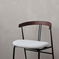 Gray upholstered seat on a sleek black metal frame with a brown wooden backrest, enhancing modern minimalism.