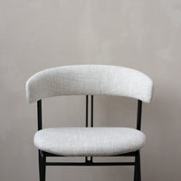 Light gray upholstered chair with a textured fabric seat and backrest, contrasted by a sleek black metal frame.