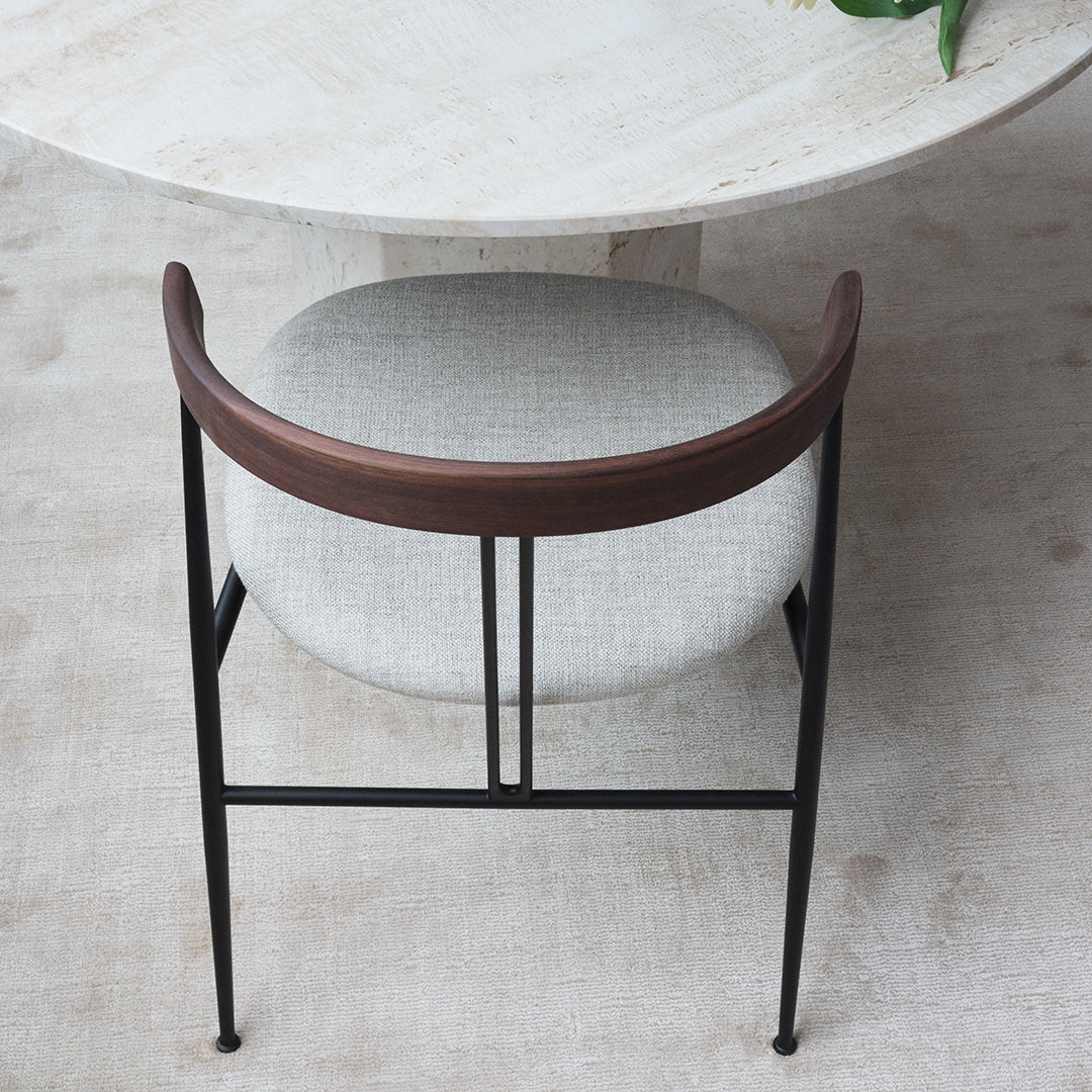 Modern black metal chair with a curved brown wooden back and soft gray upholstered seat. 