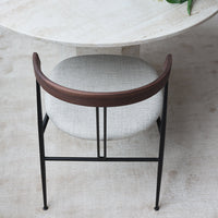 Modern black metal chair with a curved brown wooden back and soft gray upholstered seat. 
