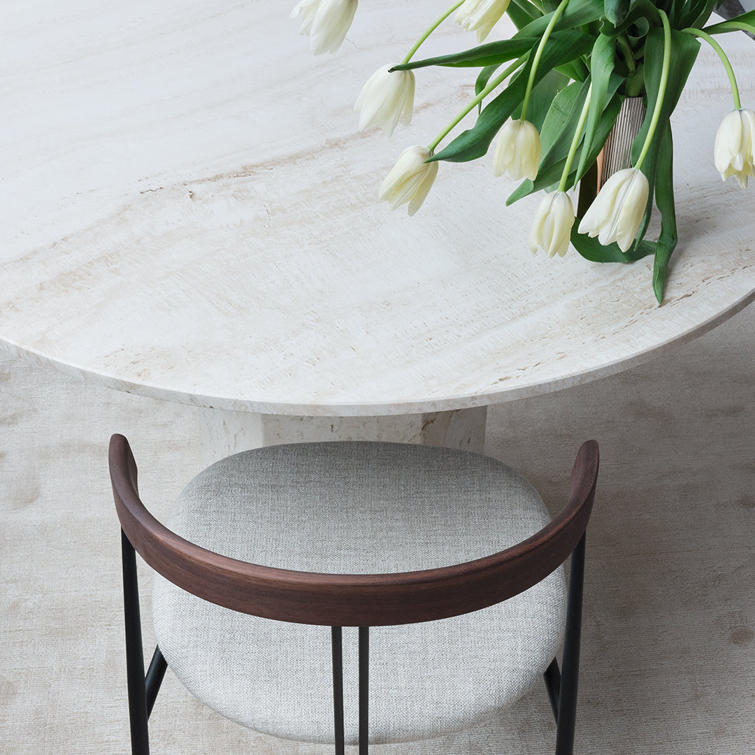 Light gray marble table with a smooth surface, paired with a soft beige upholstered chair and dark wood accents.