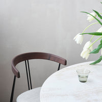 "Elegant white table with soft grain, complemented by a dark wood chair and a clear glass candle holder."