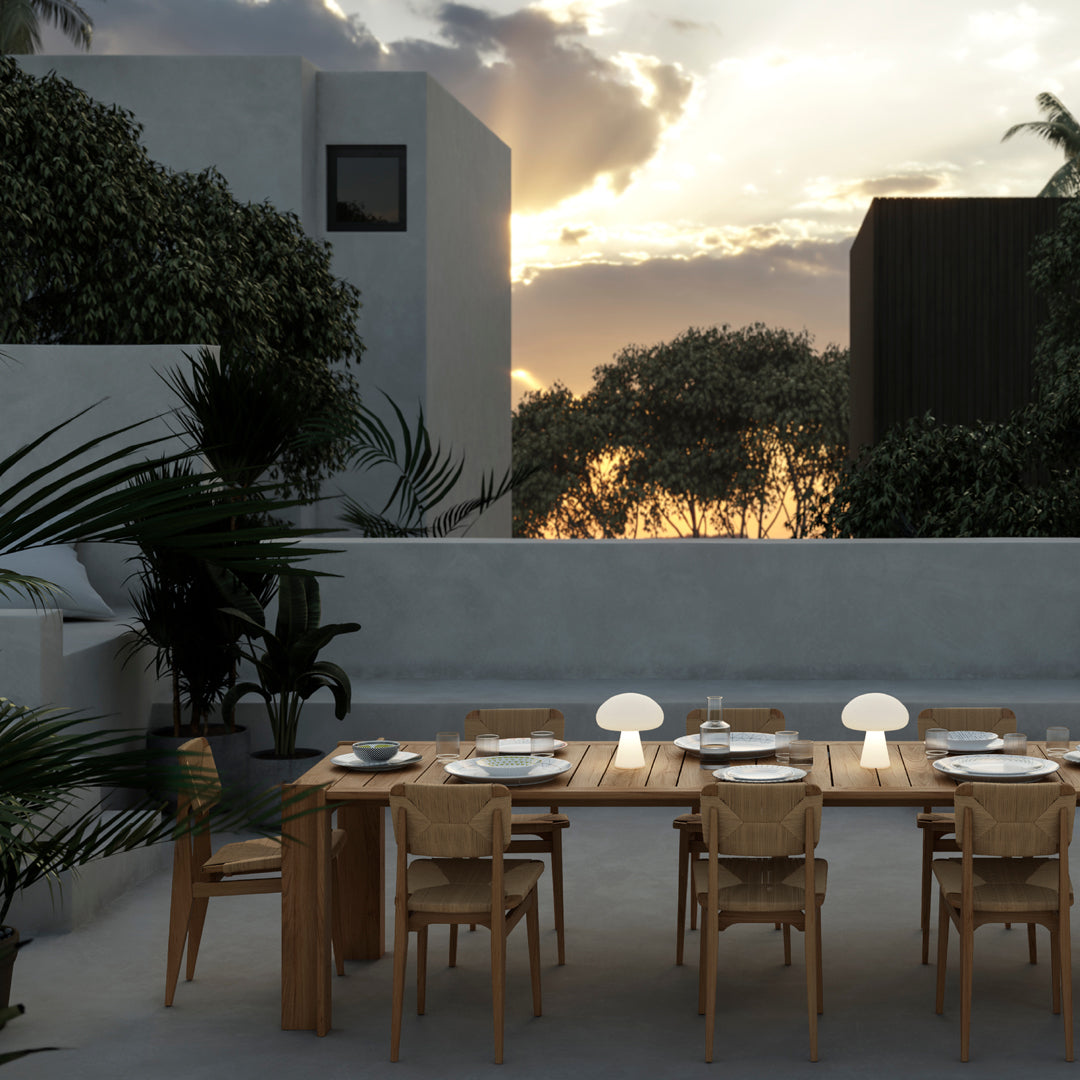 "Outdoor dining set featuring natural wood tones, woven patterns, and soft white accents against a sunset backdrop."