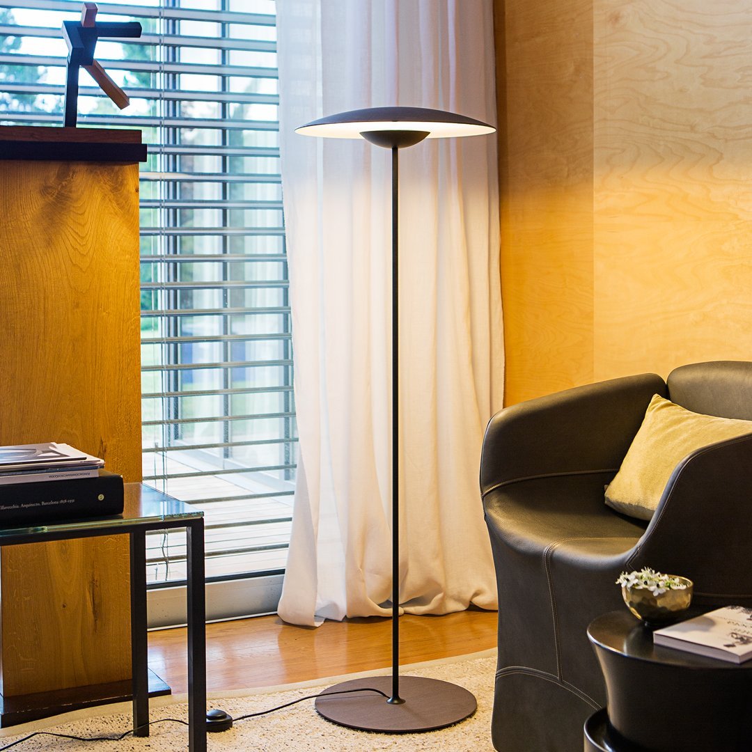 Modern floor lamp with sleek black base, circular white shade, and subtle textures, perfect for contemporary decor.
