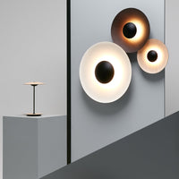 Modern wall lights in white, gold, and black circular designs against a sleek gray backdrop.