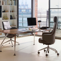 Modern office with sleek black and gray chairs, a wooden desk, and city skyline views through large windows.