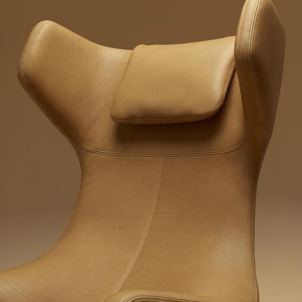 Tan leather chair with smooth texture and minimalist design, featuring a padded headrest and subtle stitching details.