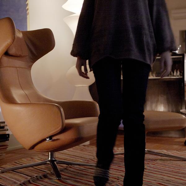 "Brown leather chair with sleek design, complemented by a striped rug in warm tones and a cozy, soft ambiance."