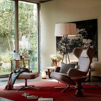 Cozy living room featuring a red rug, neutral armchair, and a mix of natural greenery and soft pastel decor elements.