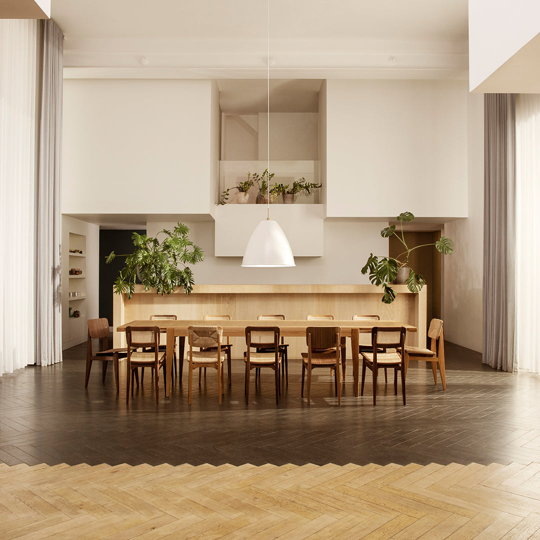Modern dining room featuring light wood tones, neutral walls, and a textured dark wood floor with subtle chevron pattern.