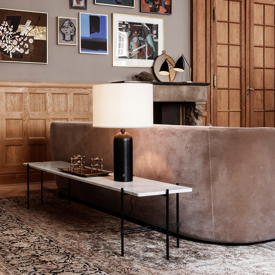 "Modern cream table with black legs, paired with a warm beige sofa and decorative patterned rug."