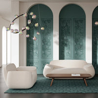 Elegant white sofa and armchair on teal patterned rug with decorative multi-colored bubble light fixture.