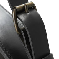 Close-up of a sleek black leather strap with a vintage brass buckle detail and smooth texture.