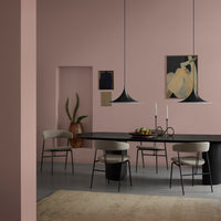 Modern dining room featuring soft pink walls, black table, and minimalist decor with earth tones and elegant lines.