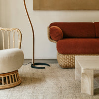 Cozy rust-colored sofa with round cushion, complemented by a light beige chair and natural woven textures.