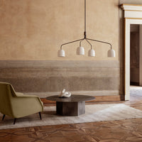 Modern chandelier with white shades and black accents, set against a warm, textured backdrop and earthy tones.