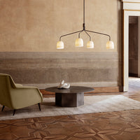 Stylish green armchair and modern gray table under soft amber glass pendant lights, set against neutral-toned walls.